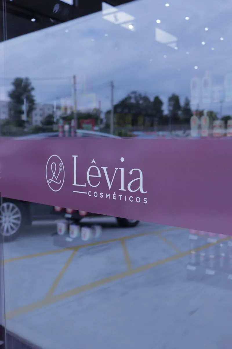 Adesivo de identidade no vidro da Lêvia Cosméticos, por D'Caris