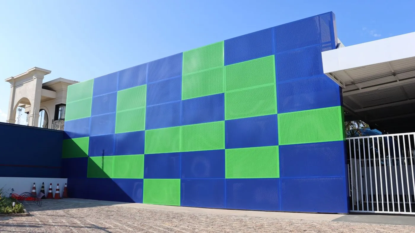 Empena em chapa metálica perfurada azul e verde do Colégio Meta